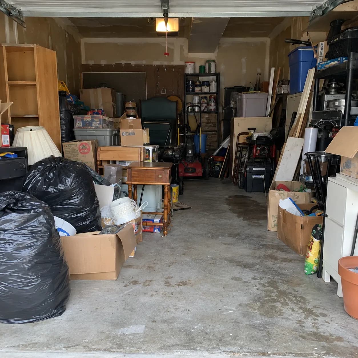 A Plano garage packed floor to ceiling with boxes, bins, timber and bagged clutter