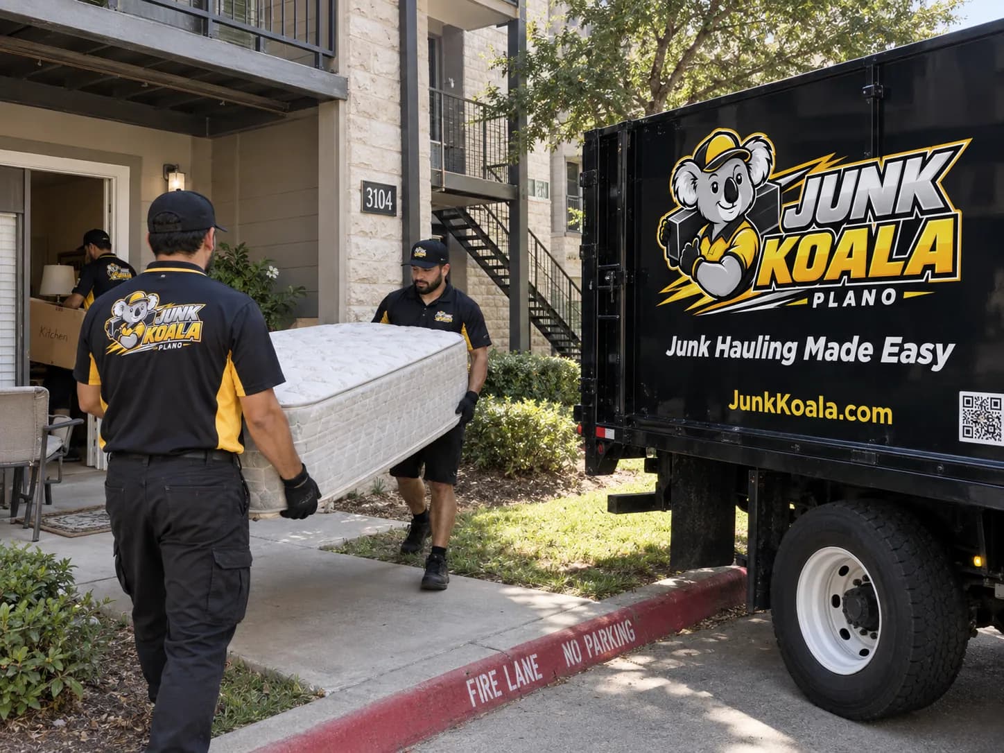 A Junk Koala Plano crew member carrying a mattress along an apartment fire lane to the truck